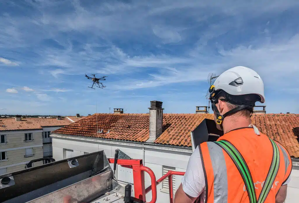 pilote en train de faire un démoussage de toiture à l'aide d'un drone