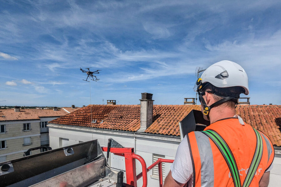 pilote en train de faire un démoussage de toiture à l'aide d'un drone